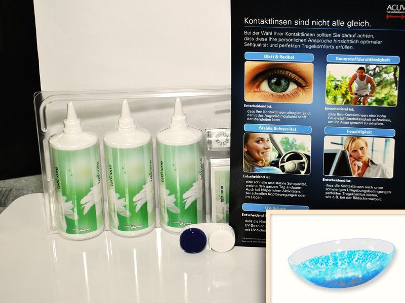 Pflegeset für Kontaktlinsen mit drei Flaschen Lösung, einem Behälter und Infotafel mit Hinweisen zur Linsenwahl.